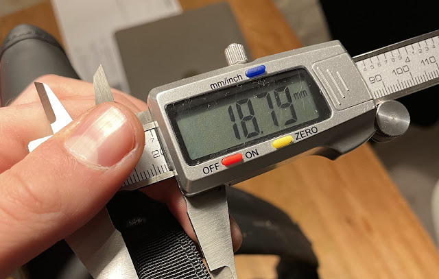A handle on a backpack being measured using a caliper
