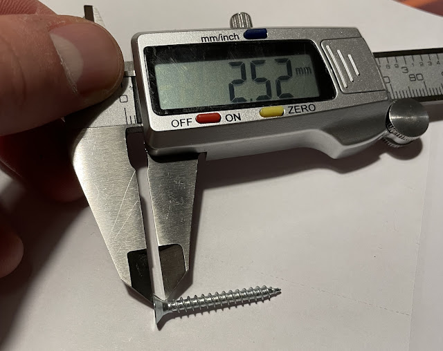 A screw head being measured with a caliper.